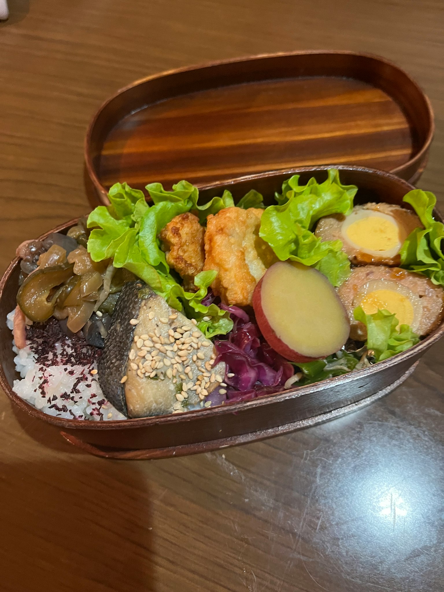 Eine Bento-Box gefüllt mit bunten Gerichten frischem Salat frittierten Lebensmitteln und Wurzelgemüse