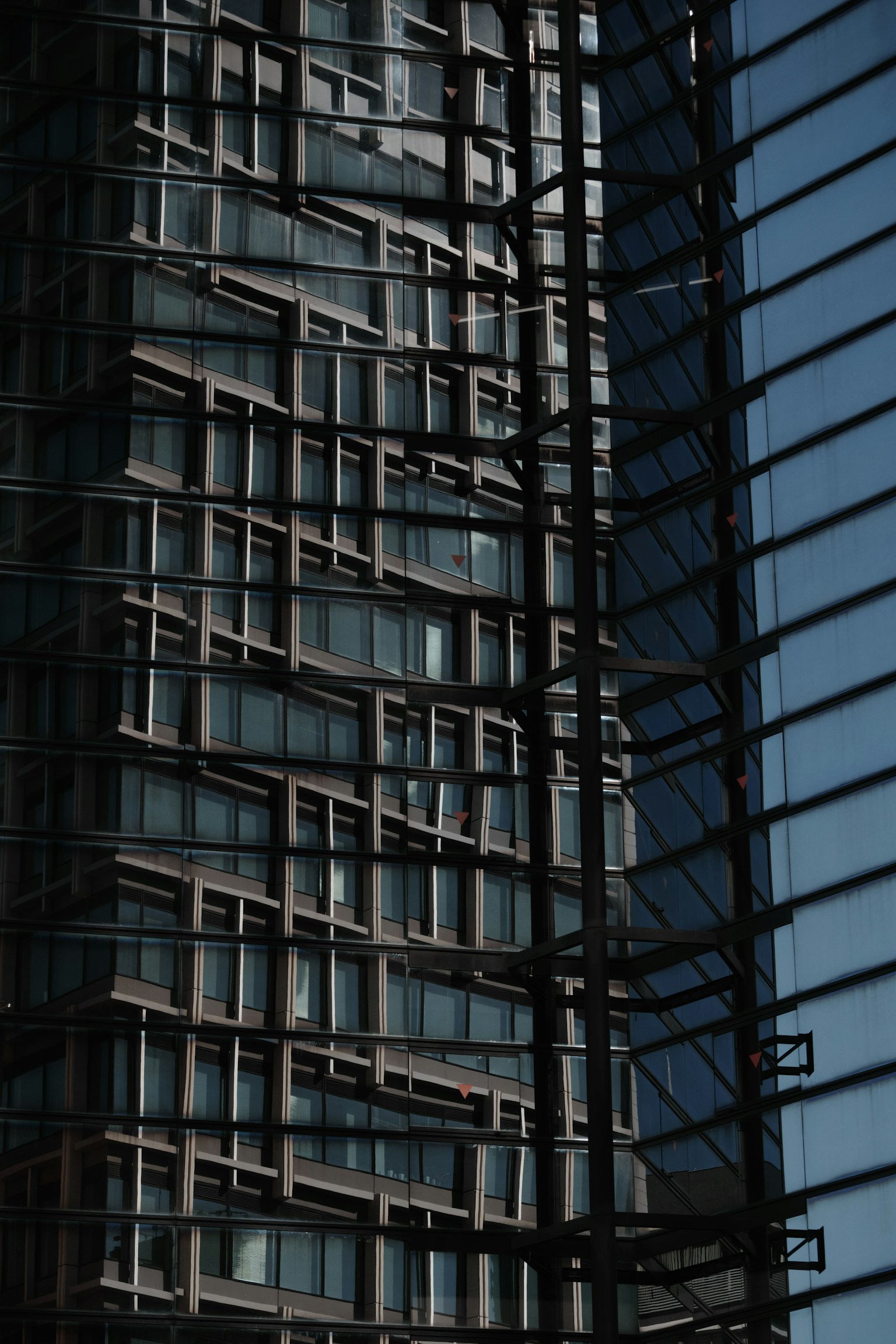 Façade d'un bâtiment moderne avec des reflets de fenêtres et un design structurel