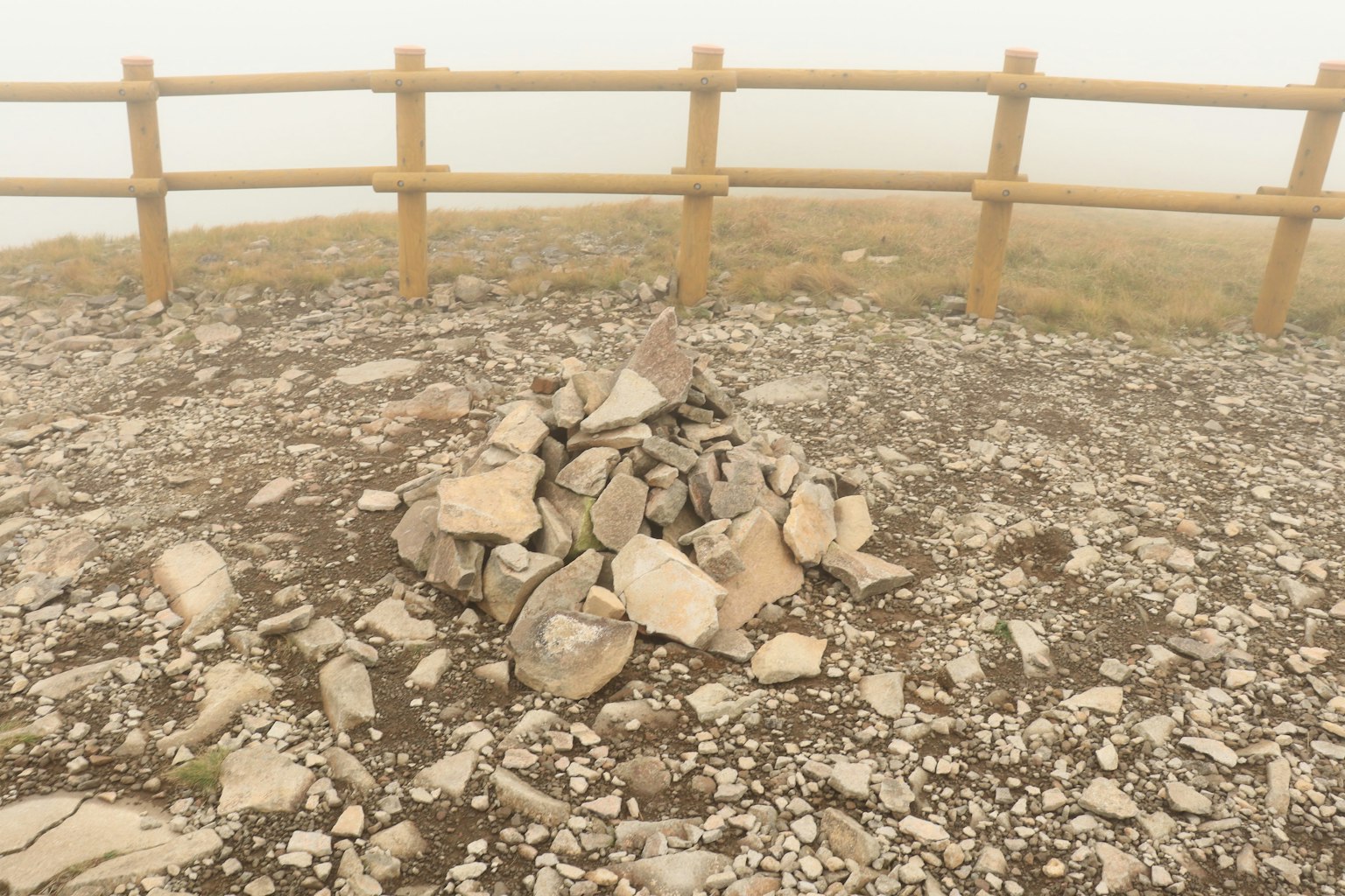 Steinhaufen im Nebel mit Holzzaun