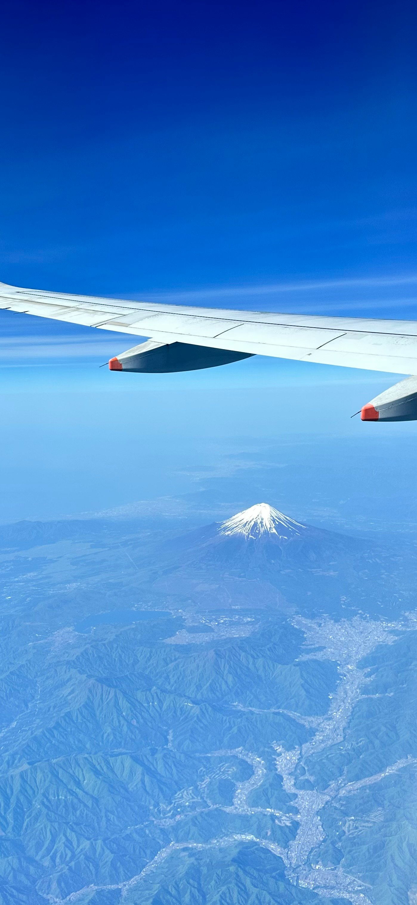 飛行機の窓から見える富士山と青い空の雲