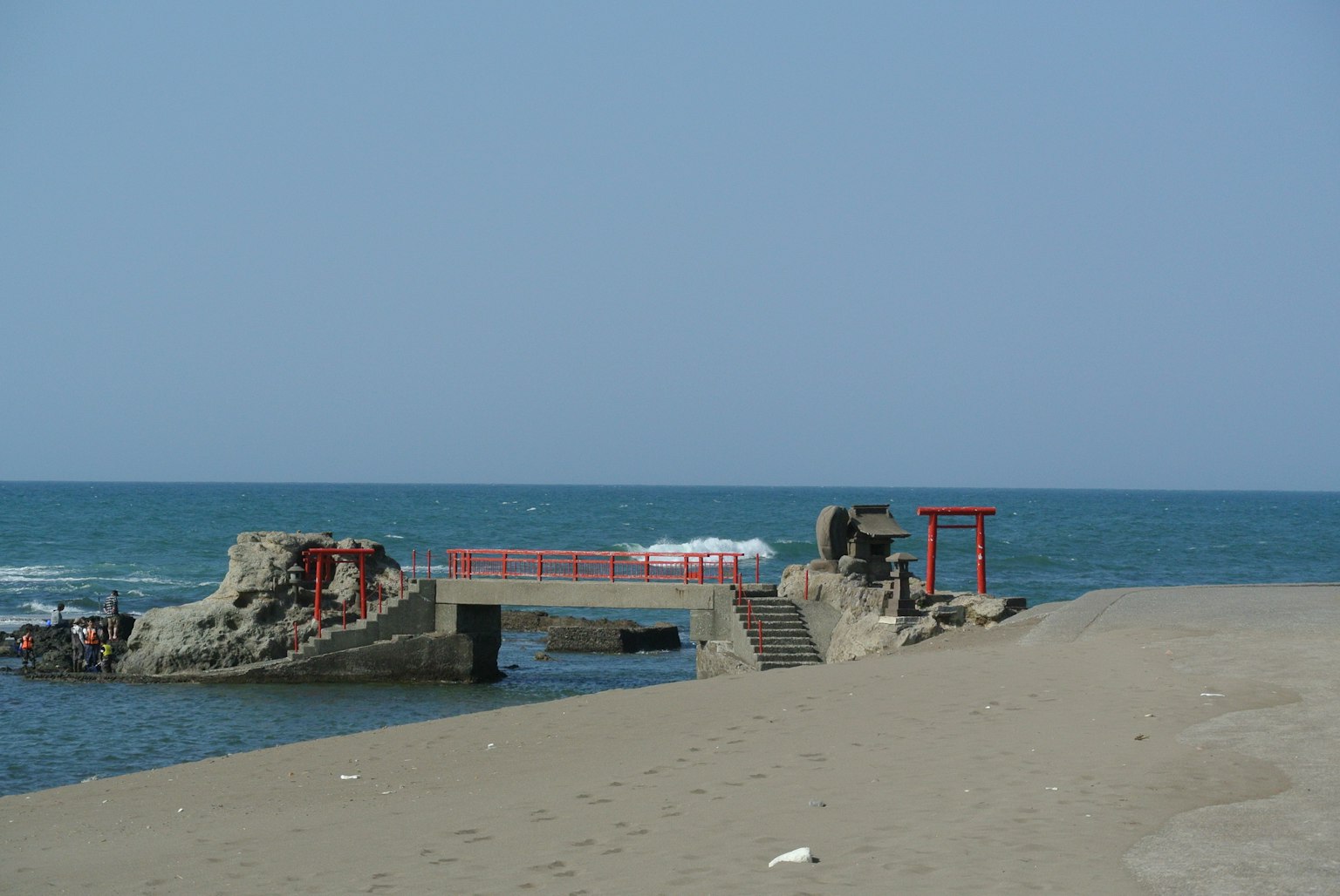 Vista panoramica di un torii rosso e di un molo rotto sulla spiaggia