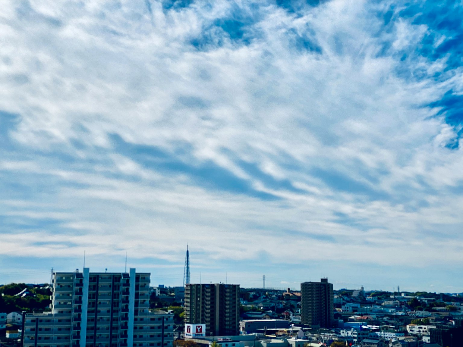 Cityscape with blue sky and clouds featuring high-rise buildings and residential areas
