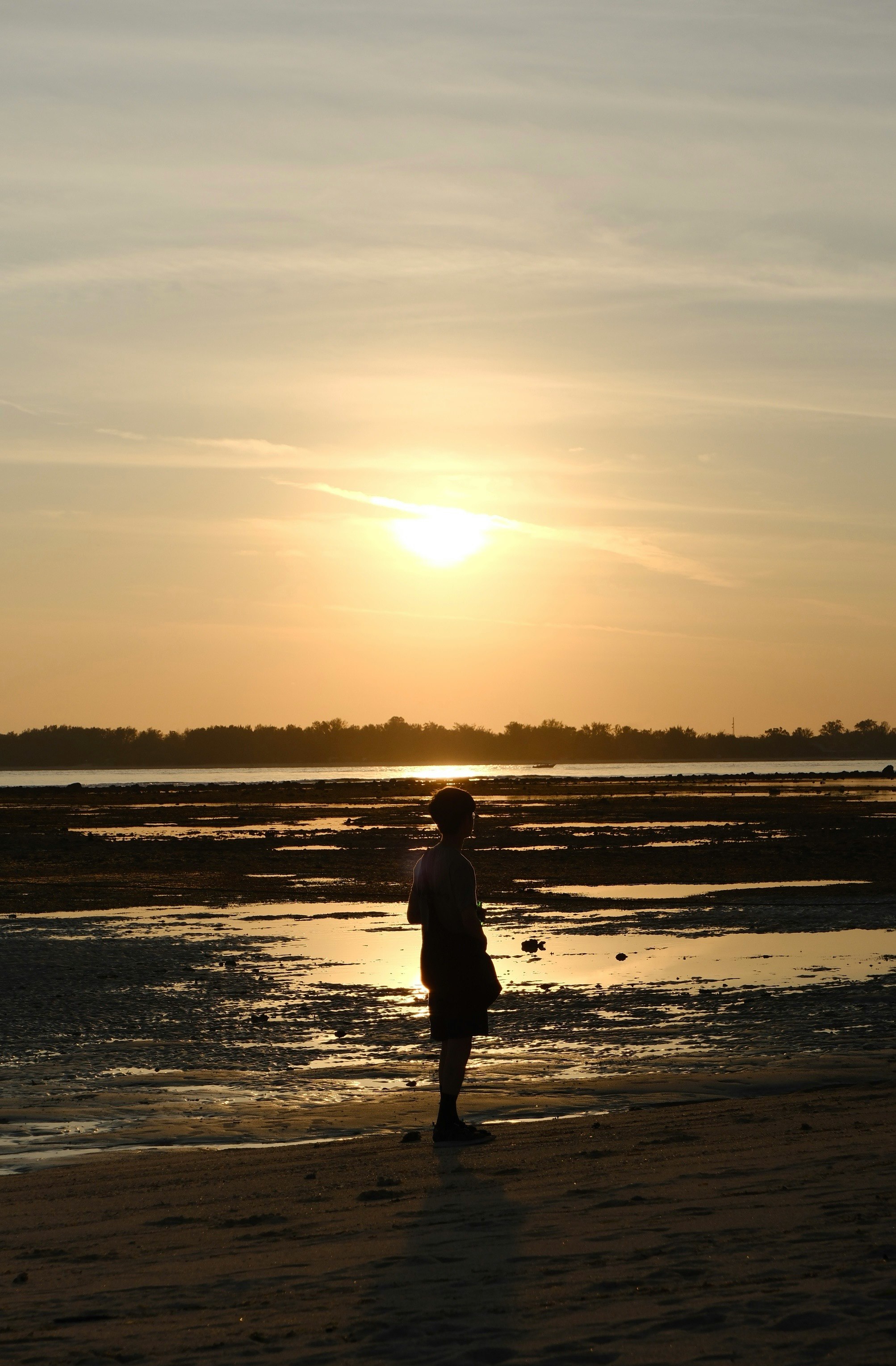 夕日に照らされた海辺を歩く人影のあるビーチ