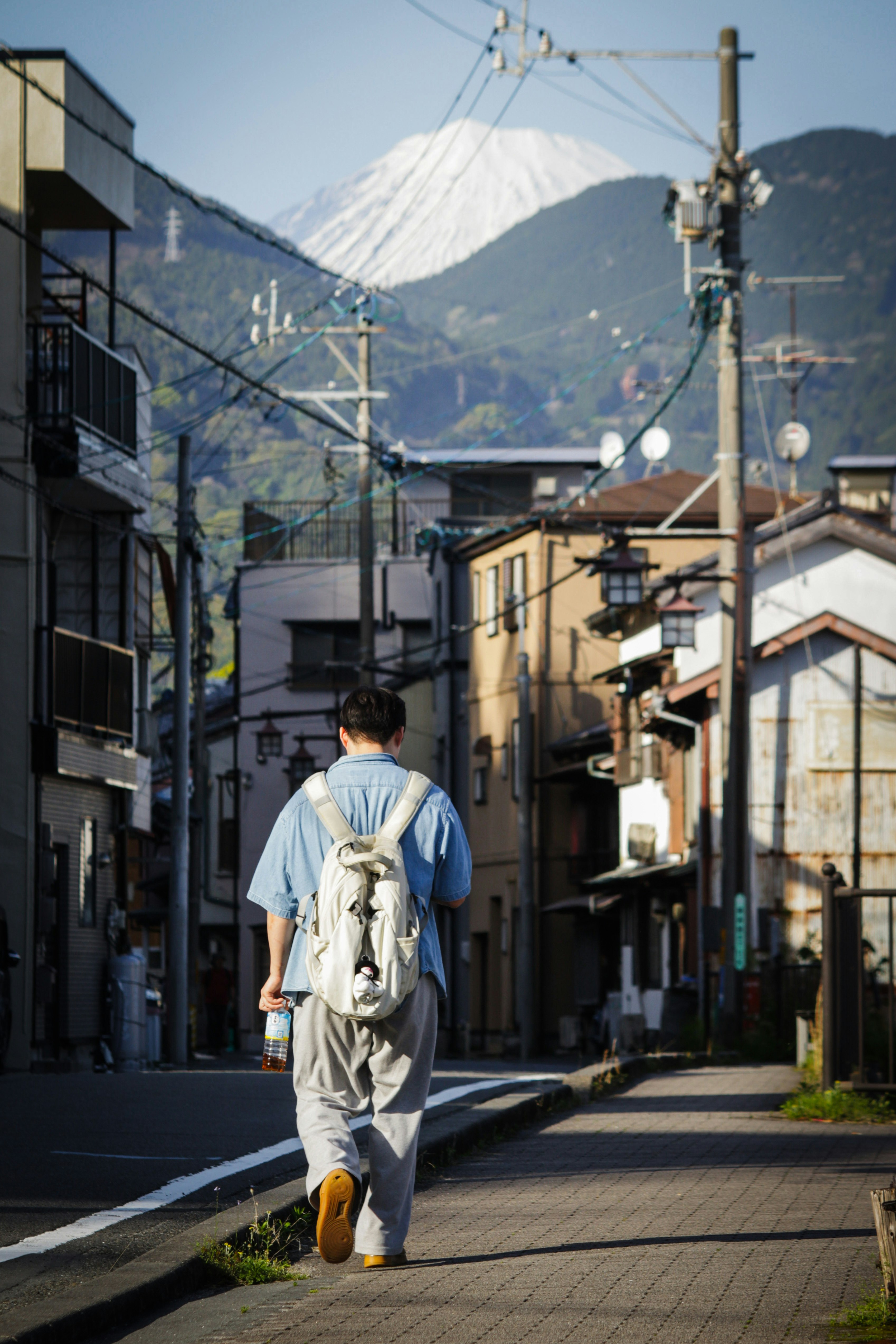 静かな路地を歩く人と遠くの雪山