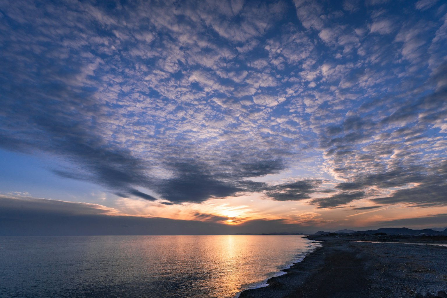 Wunderschöne Landschaft des Sonnenuntergangs über dem Meer mit blauem Himmel und Wolken