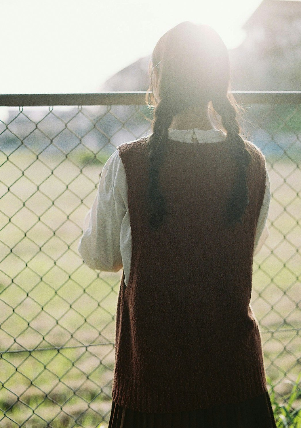 ผู้หญิงยืนในแสงย้อนใกล้รั้ว