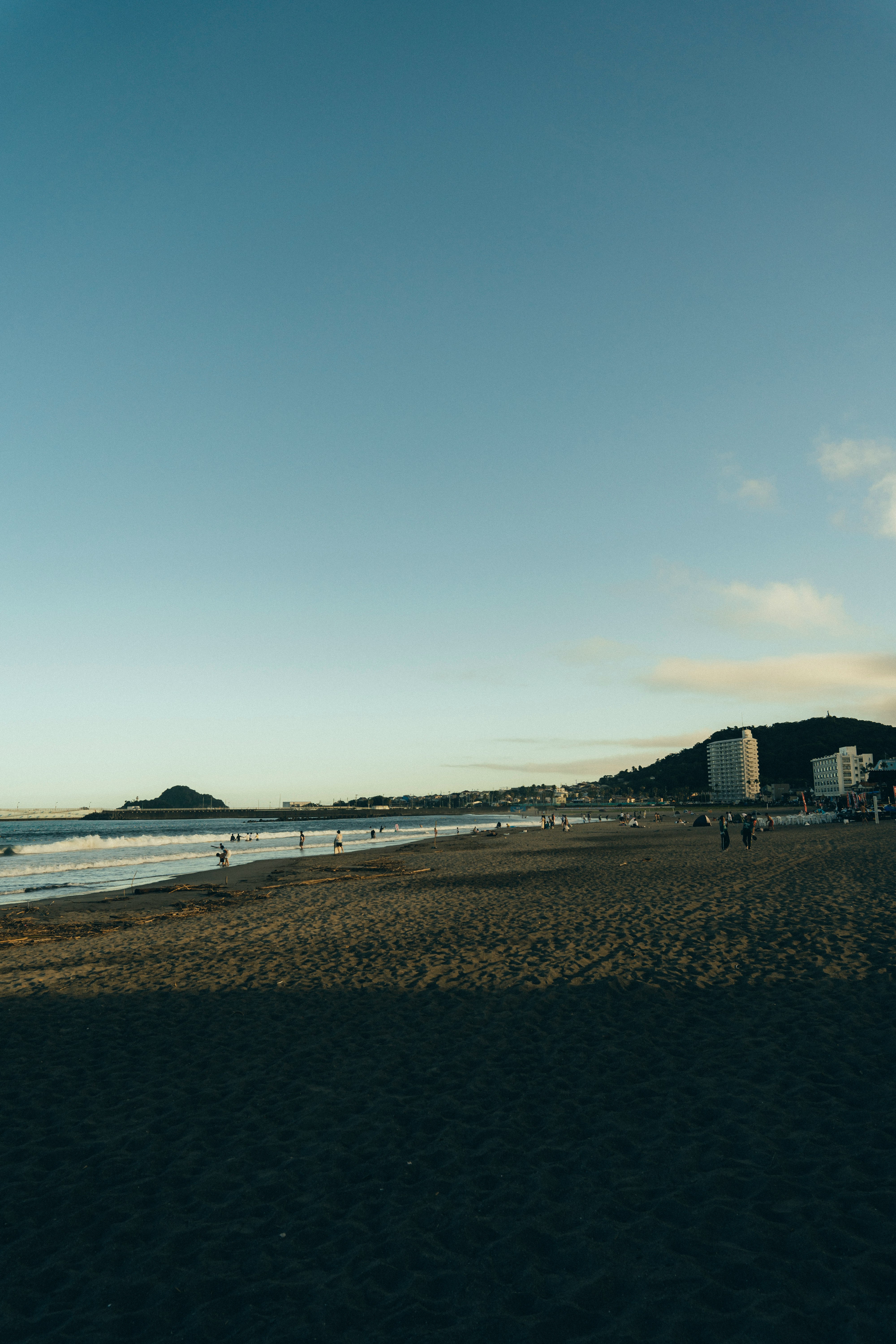 Seaside sandy beach with a distant headland and buildings along the coast