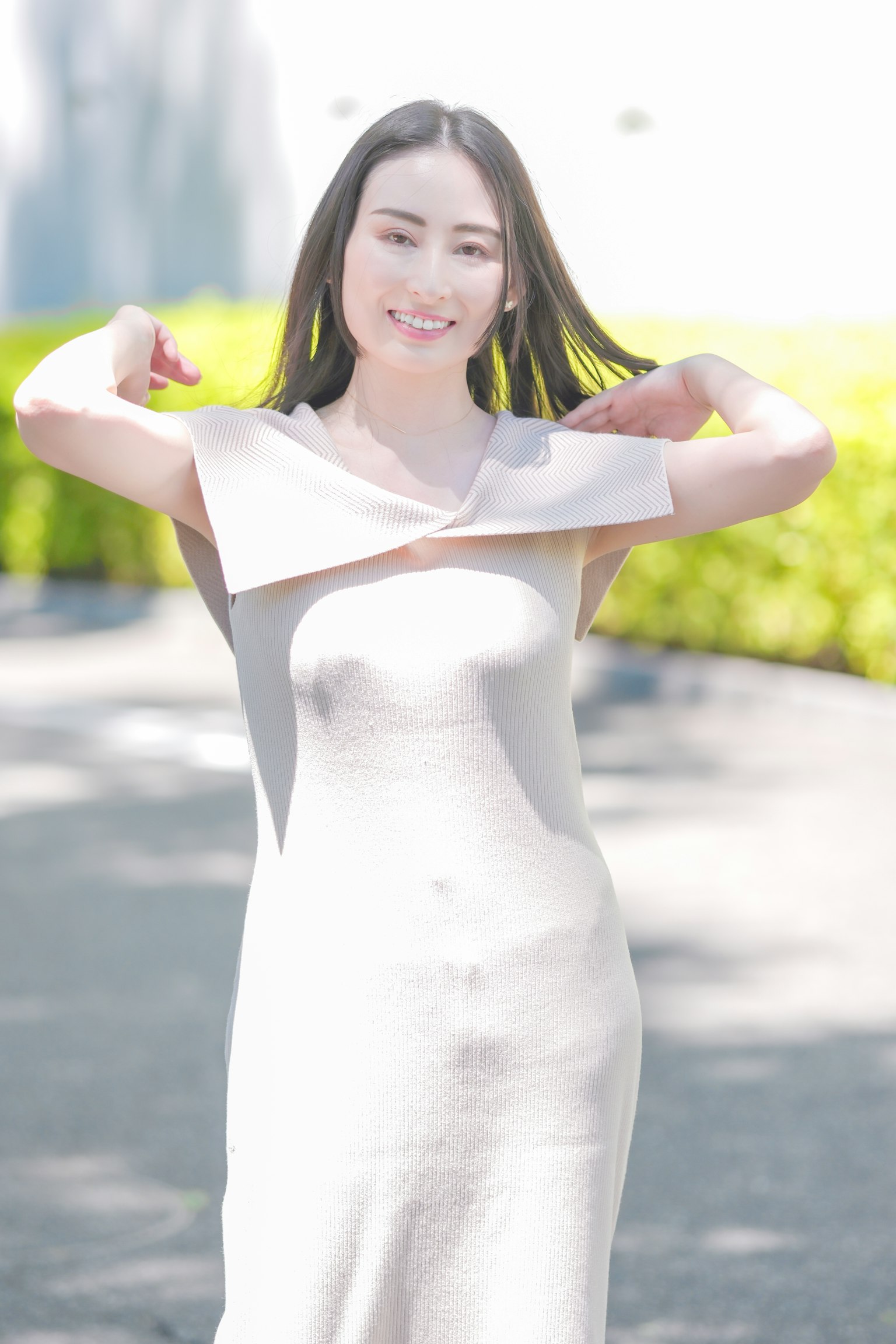 ผู้หญิงในชุดสีขาวยิ้มและโพสท่ากลางแจ้ง