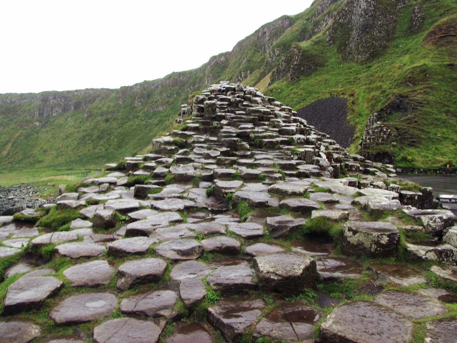 Formation de pierres hexagonales au Chaussée des Géants en Irlande avec des collines verdoyantes