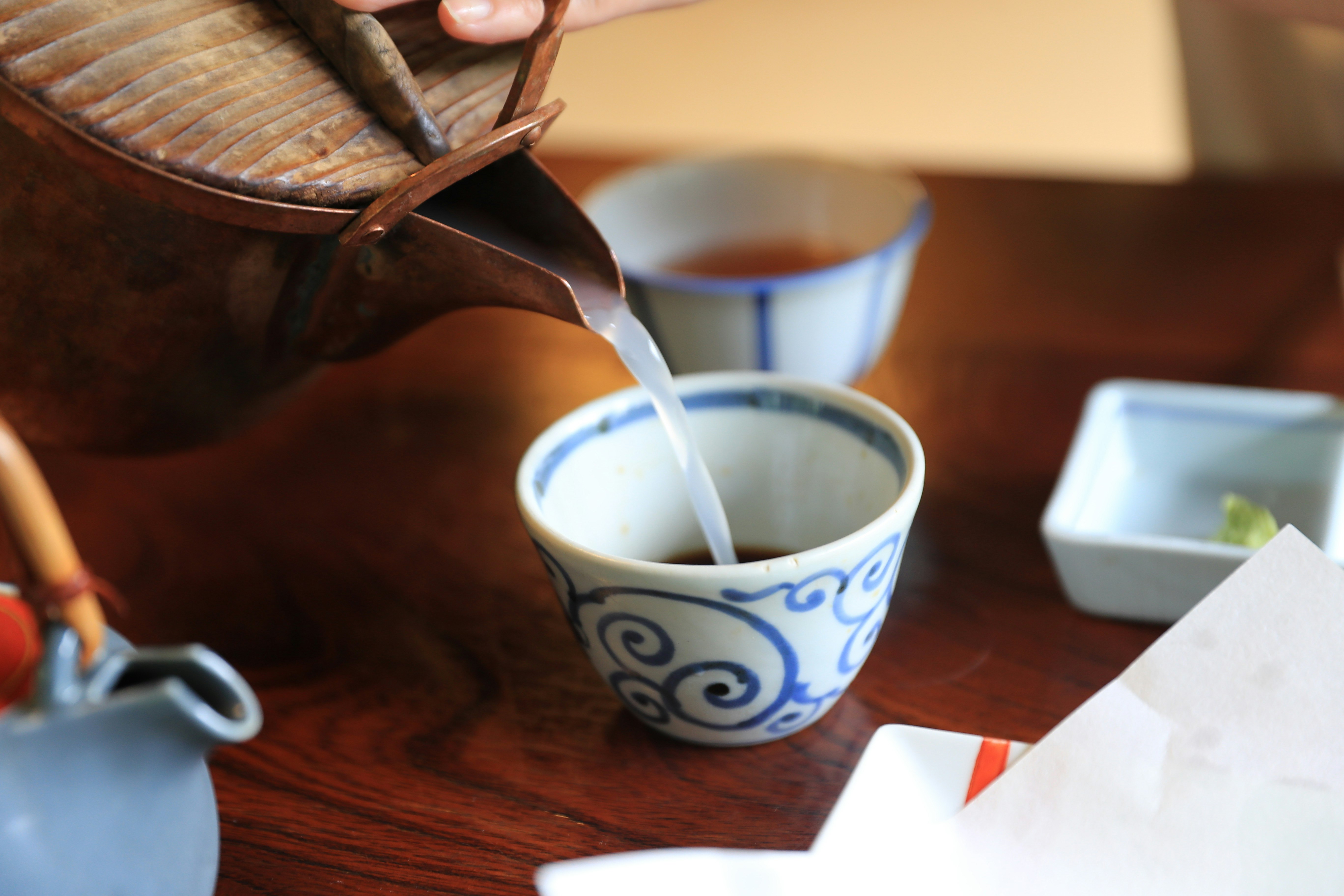 把蕎麦汤（そば湯）倒入小茶杯的手与餐桌