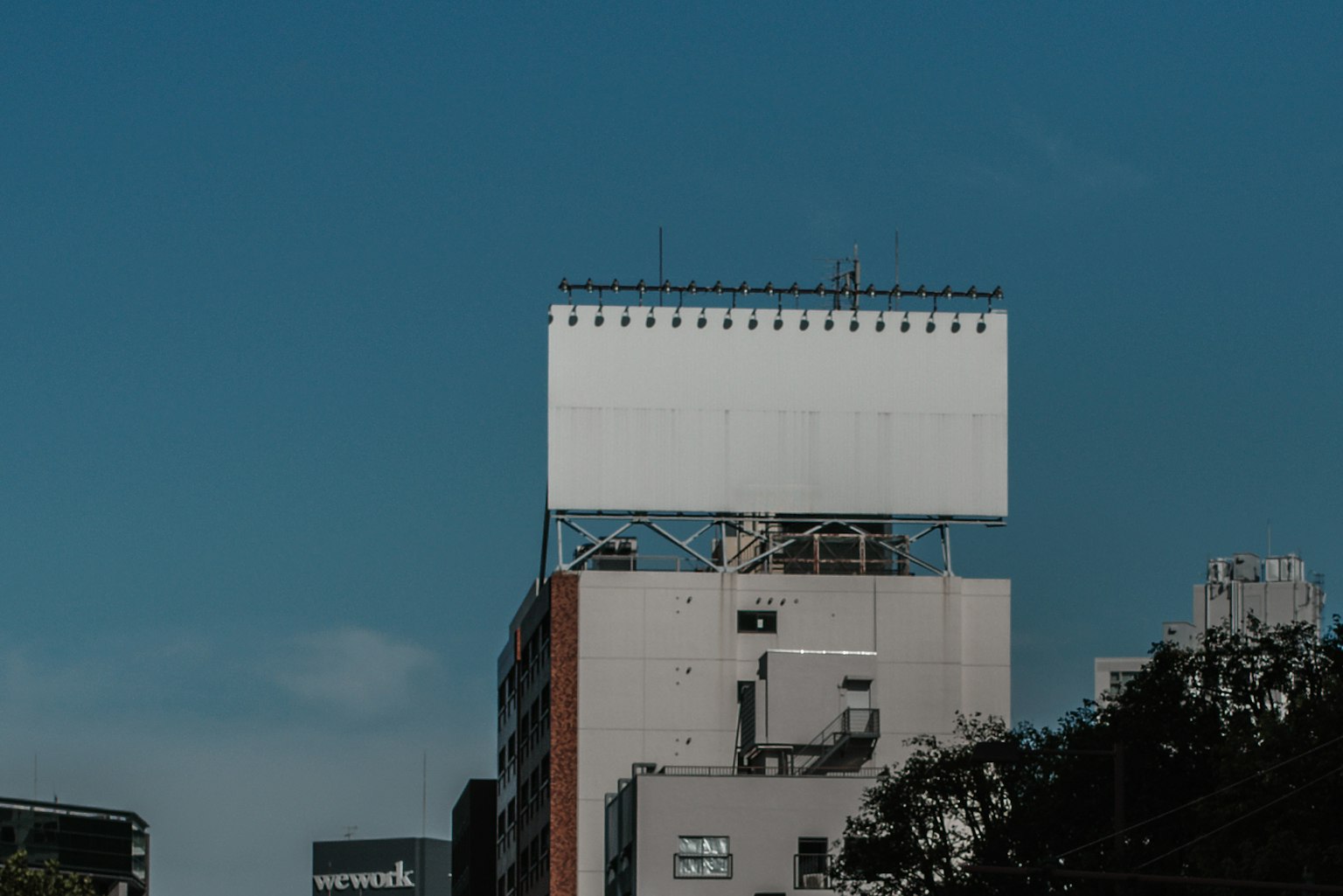 Empty billboard on top of a high-rise building under a clear blue sky