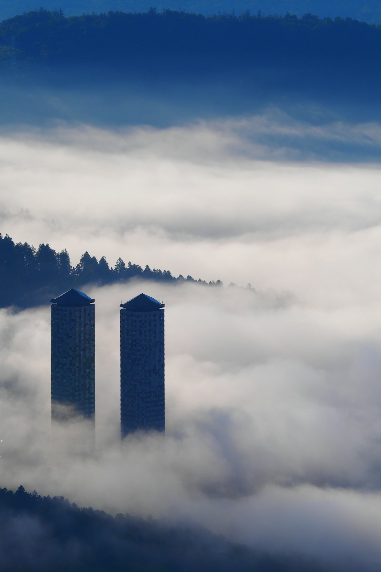 Due alti edifici che emergono da un paesaggio nebbioso