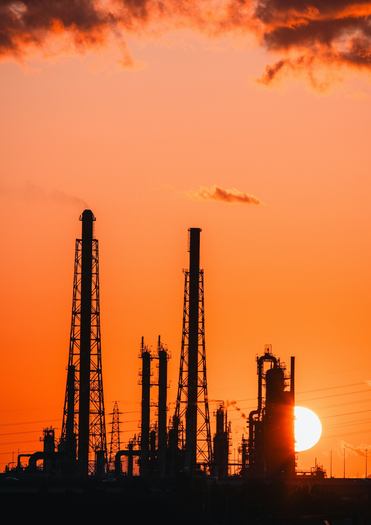 夕日を背景にした工場のシルエット 高い煙突と産業設備が並ぶ