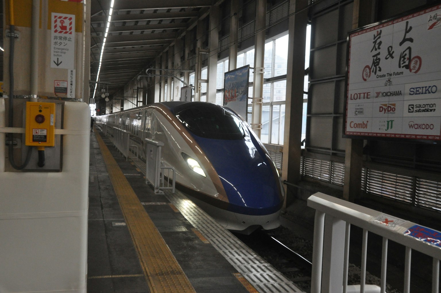 รถไฟชินคันเซ็นมาถึงสถานีพร้อมโครงสร้างชานชาลาที่มองเห็นได้และแสงสว่างที่สดใส