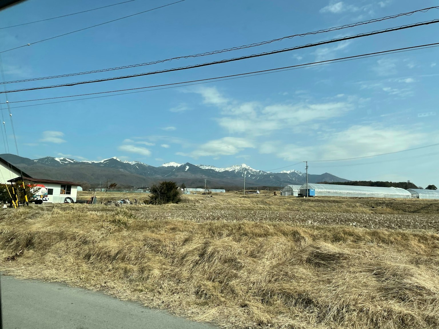 A landscape featuring dry grassland and distant snow-capped mountains