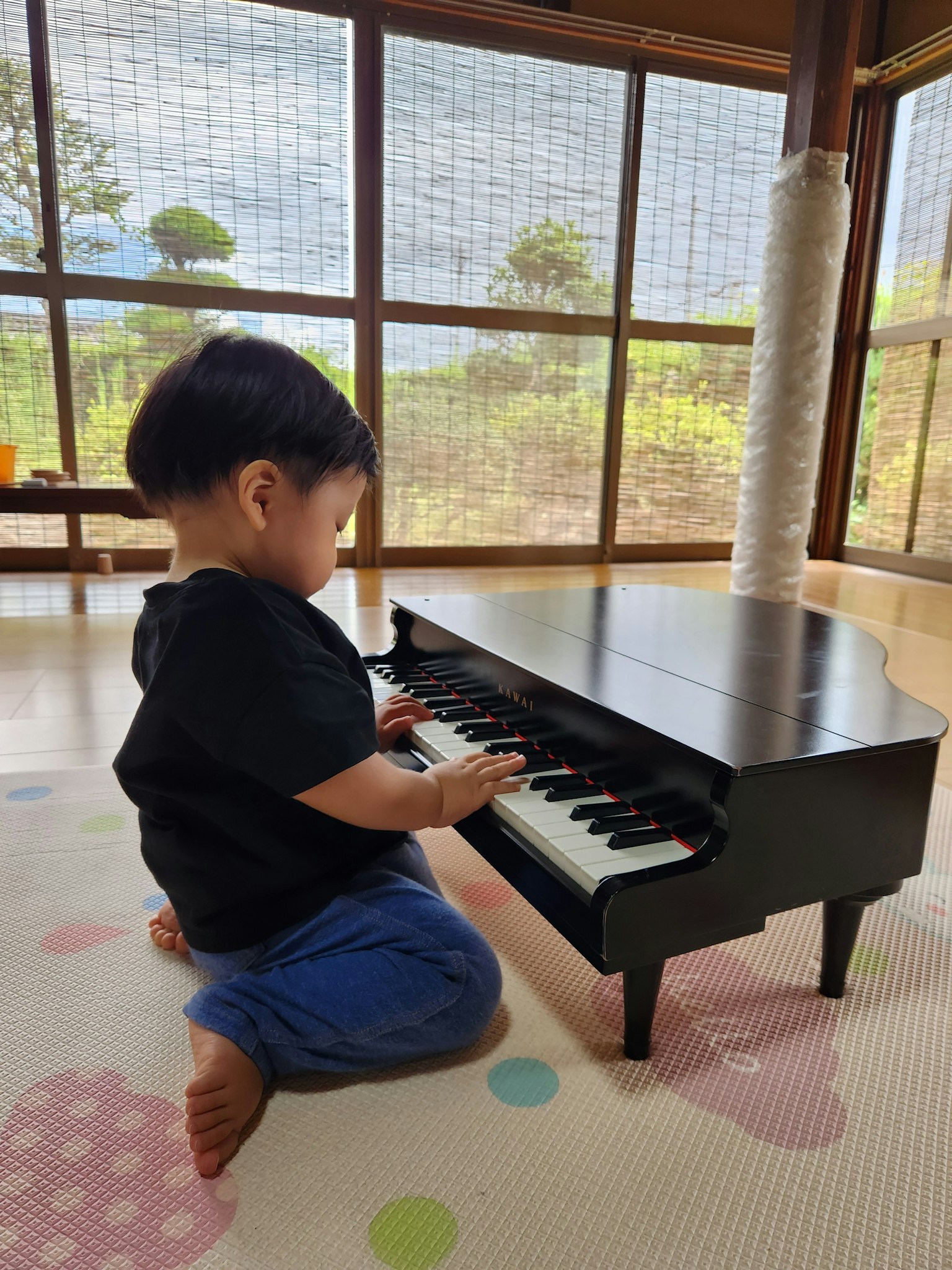 一个小孩在明亮的室内空间弹奏黑色迷你钢琴