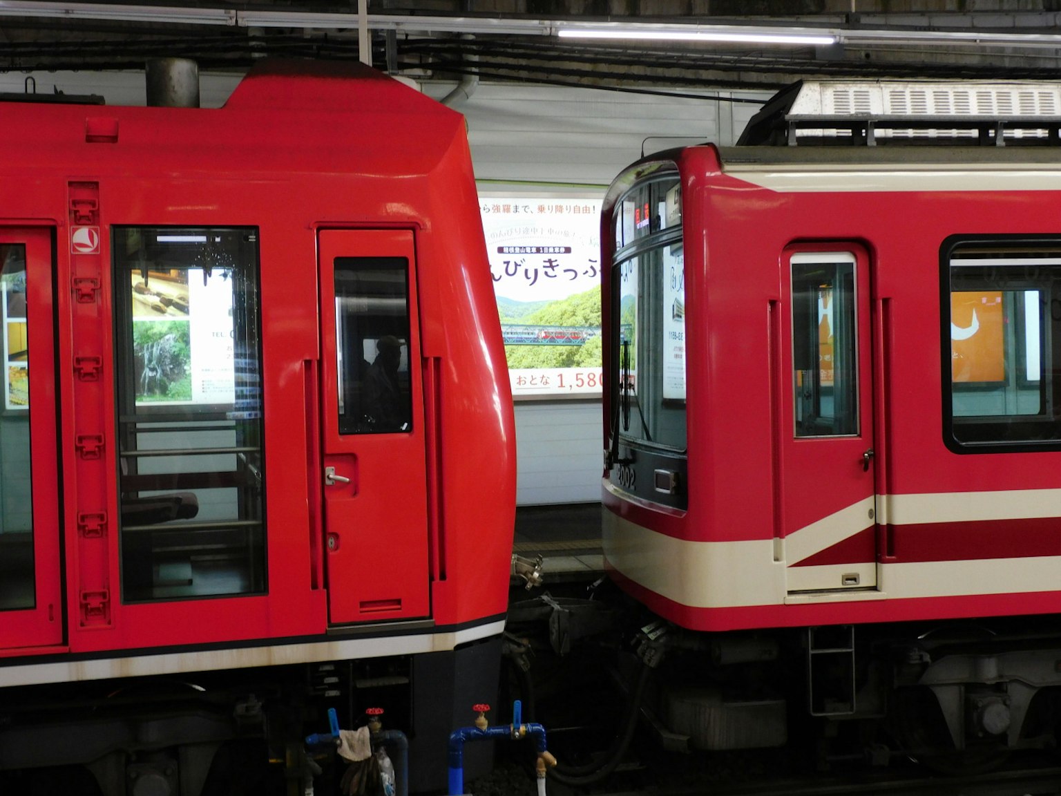 Dua kereta merah berdampingan di stasiun