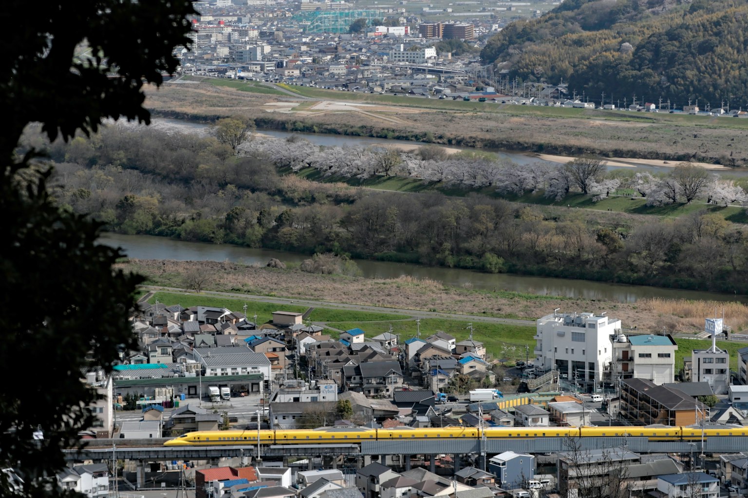 从山上俯瞰城镇和河流 有一列黄色火车经过