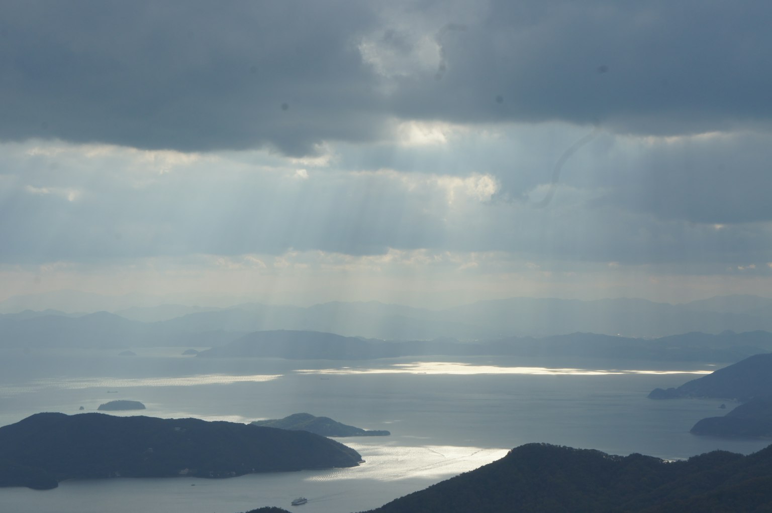 Vista majestuosa del mar desde la montaña rayos de luz rompiendo a través del cielo nublado