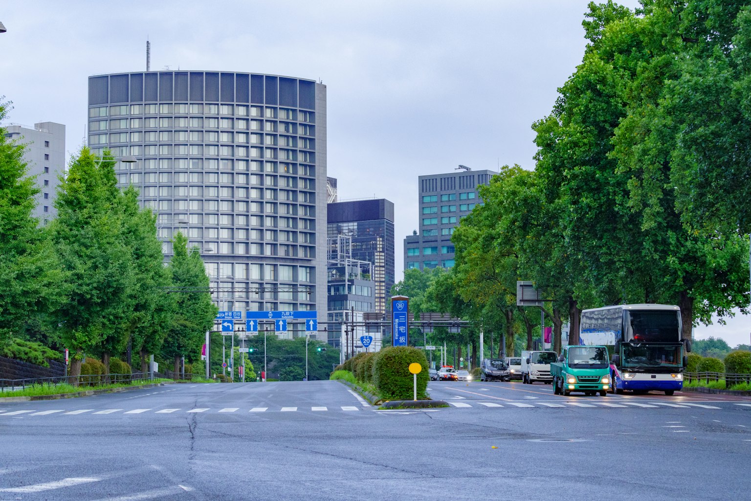 Jalan perkotaan dengan gedung tinggi dan pepohonan hijau