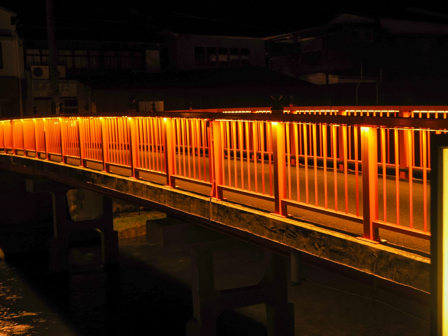 Pont orange lumineux sur une rivière la nuit
