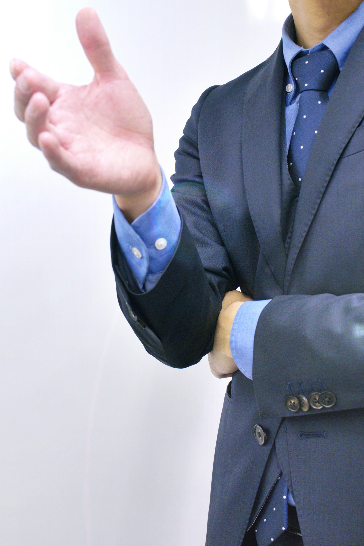 ชายในชุดสูทธุรกิจที่เห็นแขนหนึ่งข้างและมือกำลัง gesturing เหมือนพูด