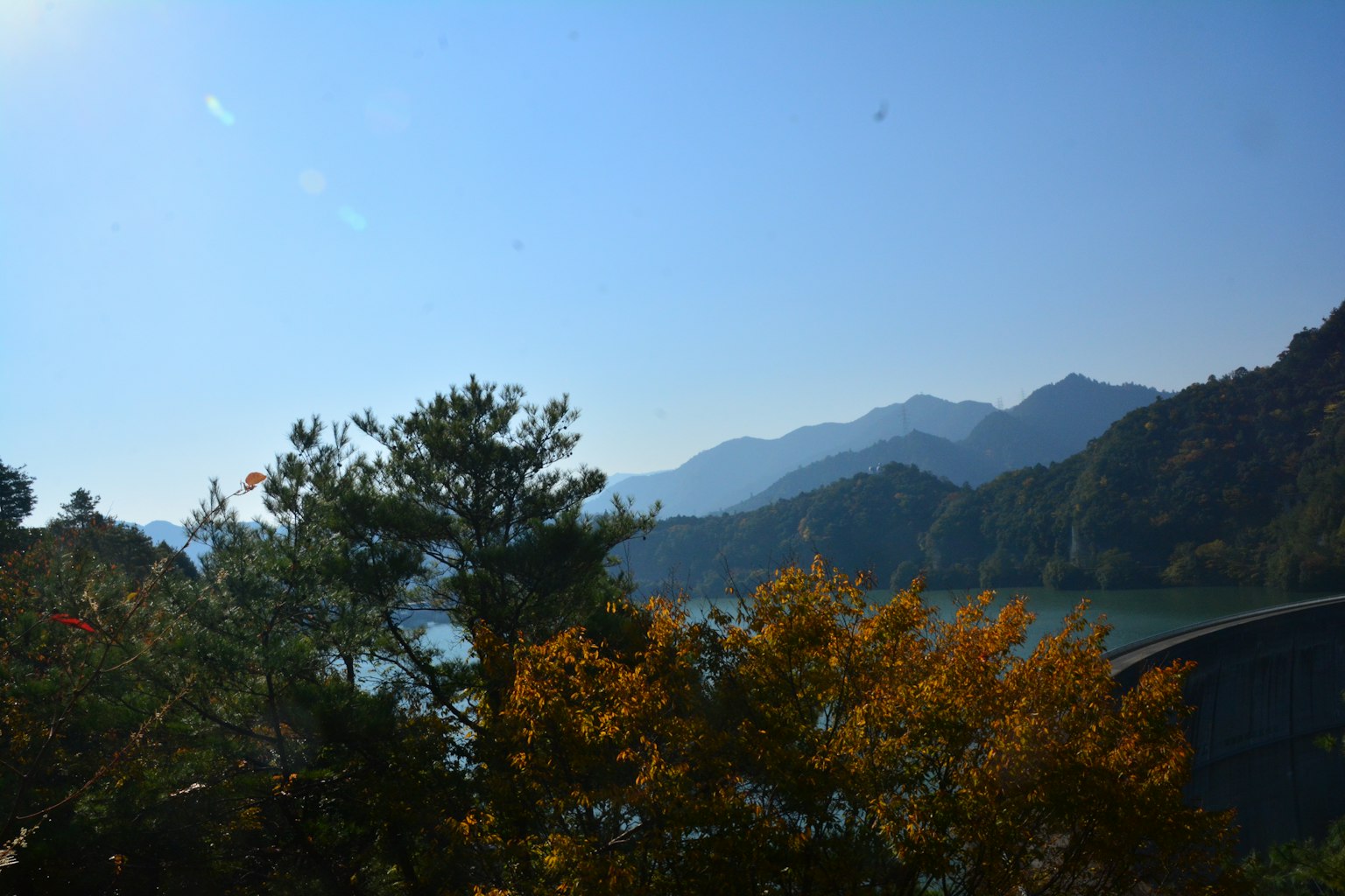 Vista panoramica di montagne e alberi autunnali sotto un cielo blu sereno