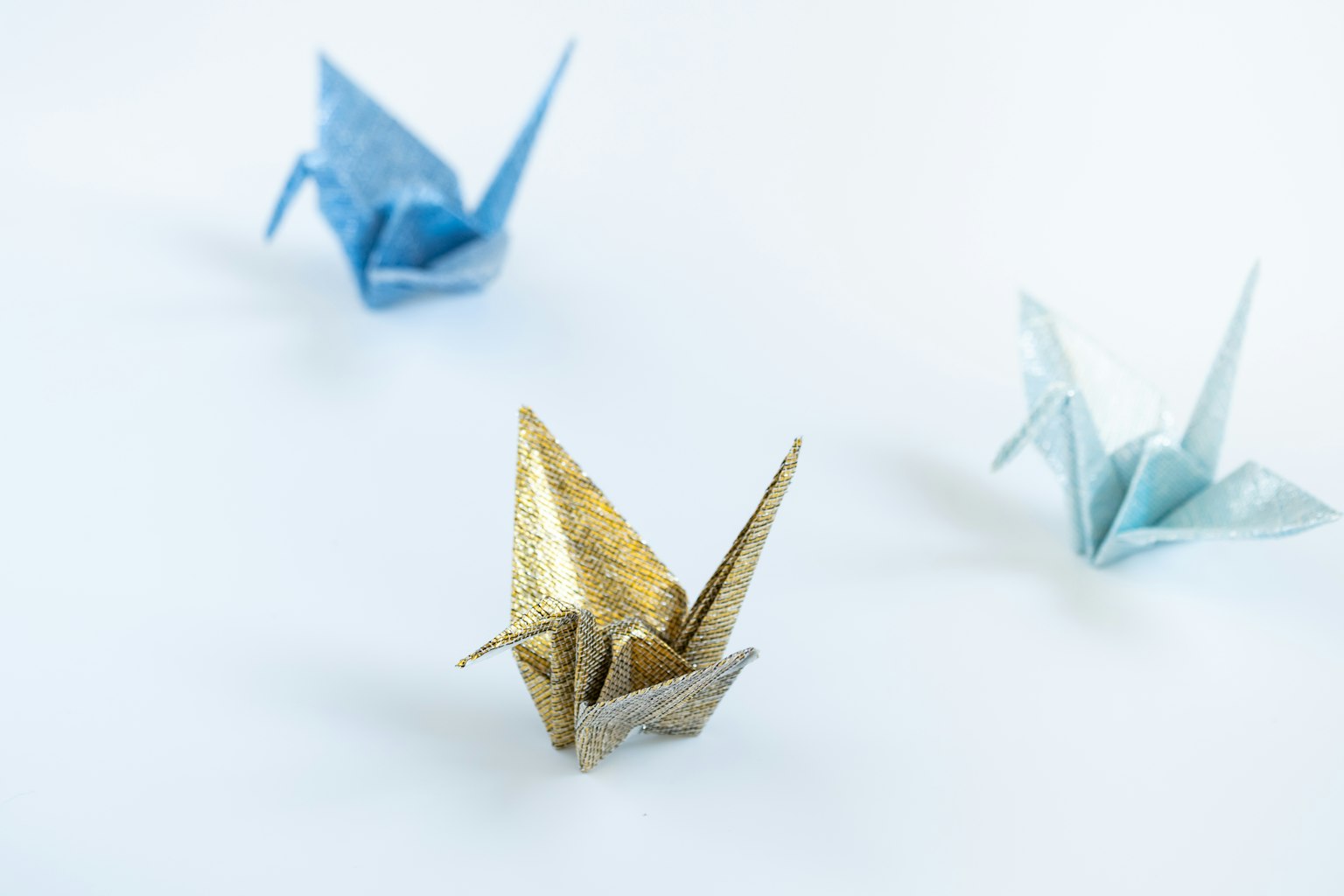 Gru in origami blu e dorate su sfondo bianco