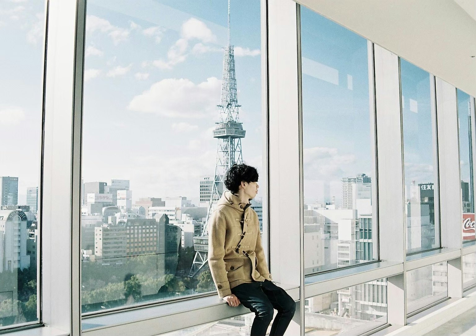 Người đàn ông ngồi bên cửa sổ với cảnh tháp Tokyo