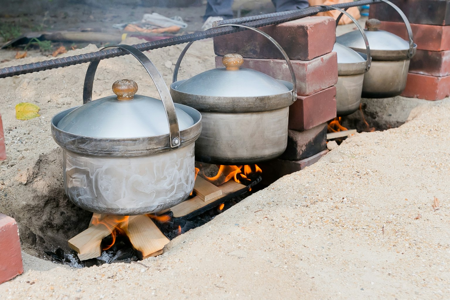 Fila de ollas de metal cocinando sobre un fuego al aire libre Humo saliendo de las ollas