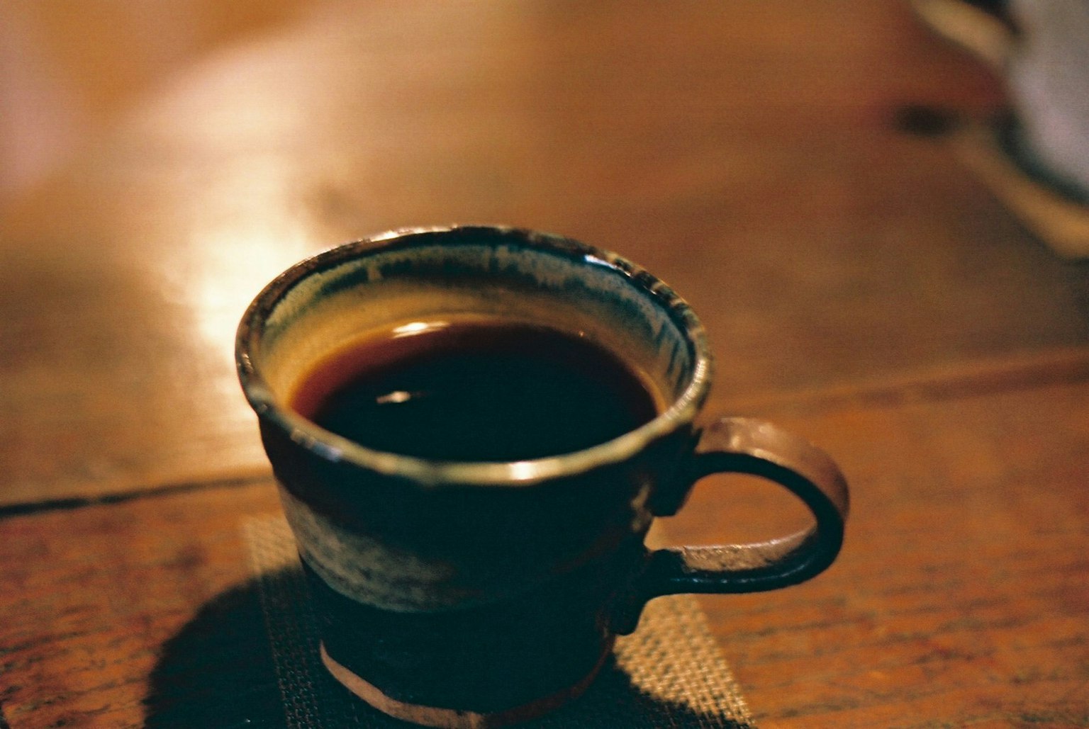 Une tasse en céramique bleue remplie de café posée sur une table en bois