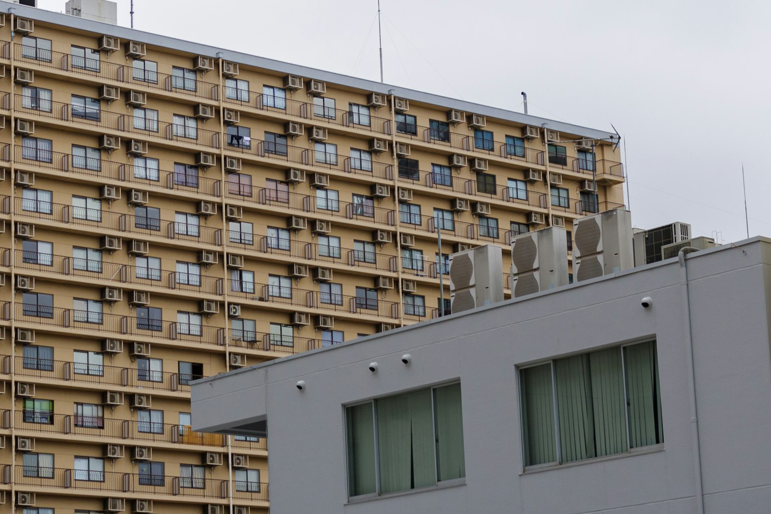 Image montrant un bâtiment gris avec un immeuble jaune en arrière-plan
