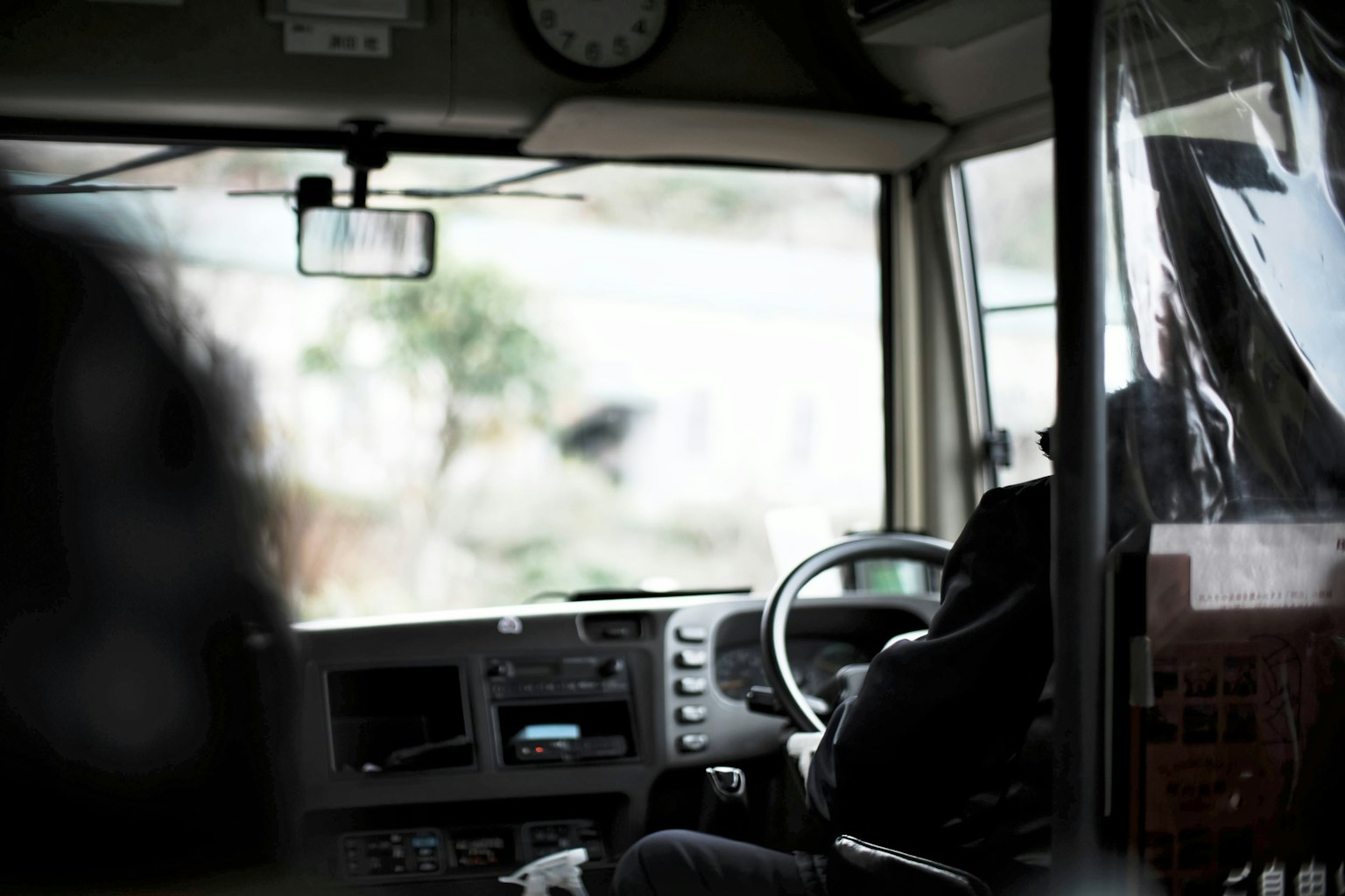 Interior kursi pengemudi bus menunjukkan punggung pengemudi dan kontrol bus