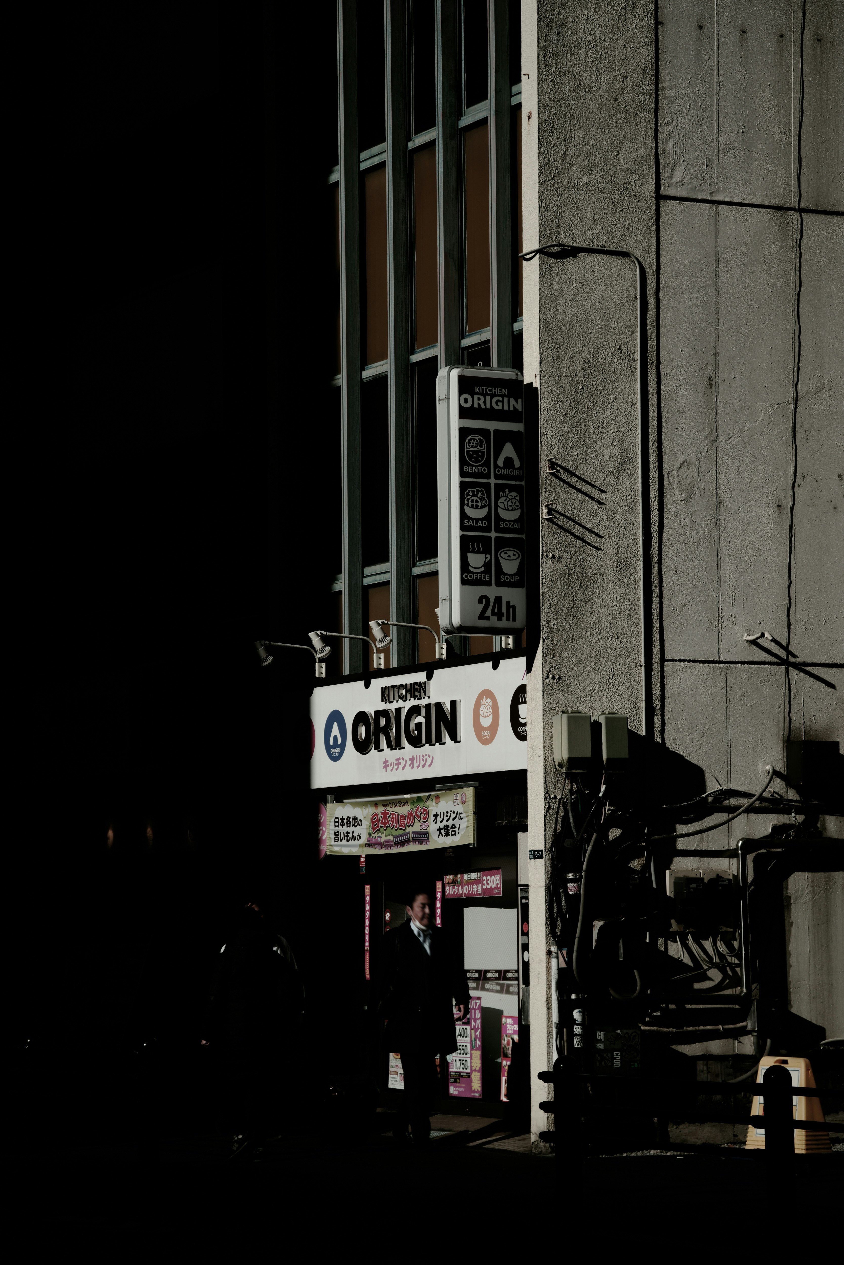 enseigne « ORIGIN » pour bento sur un mur d’une ruelle avec une moto de livraison