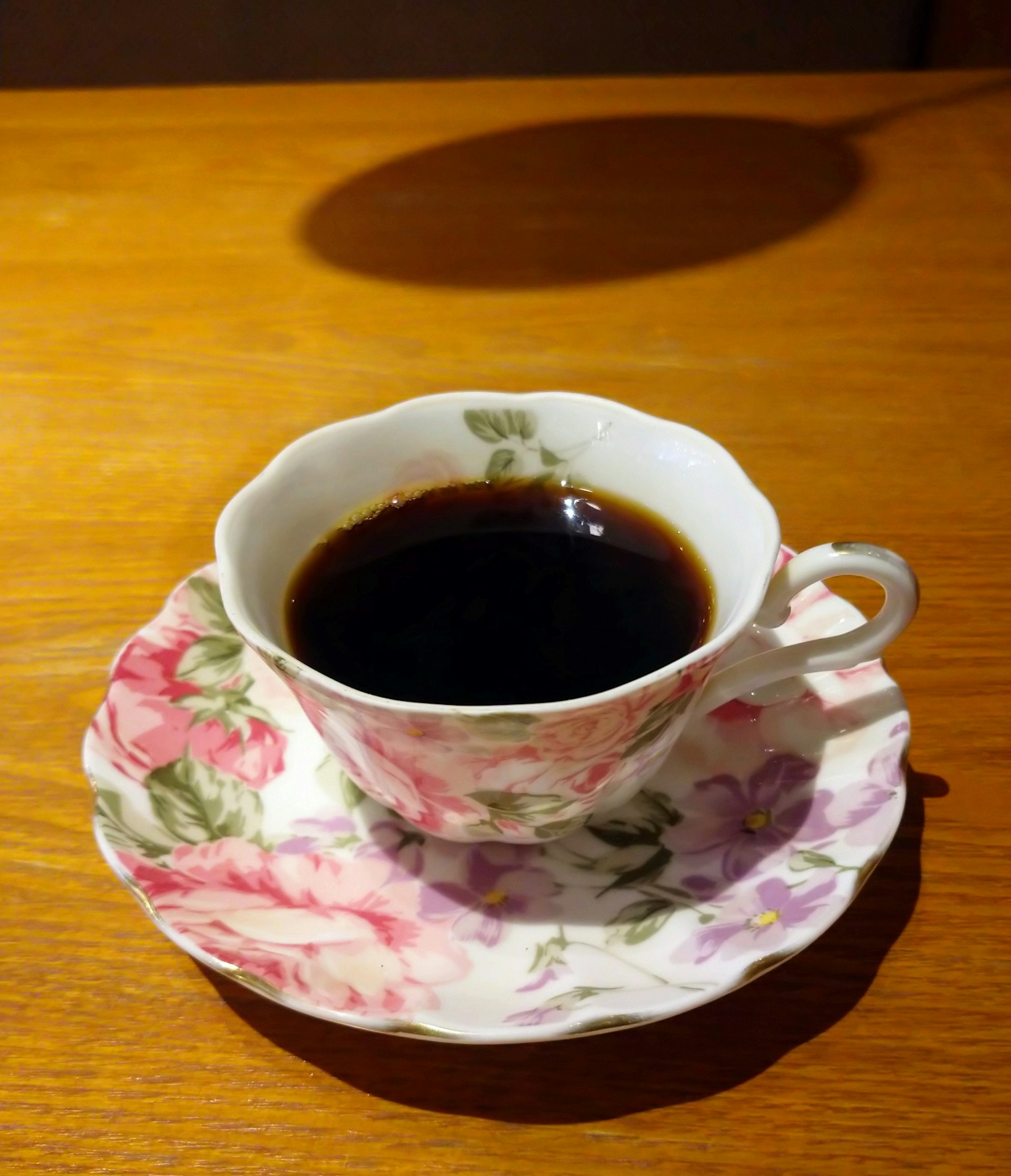 กาแฟดำในถ้วยลายดอกไม้พร้อมจานรองที่เข้าชุด