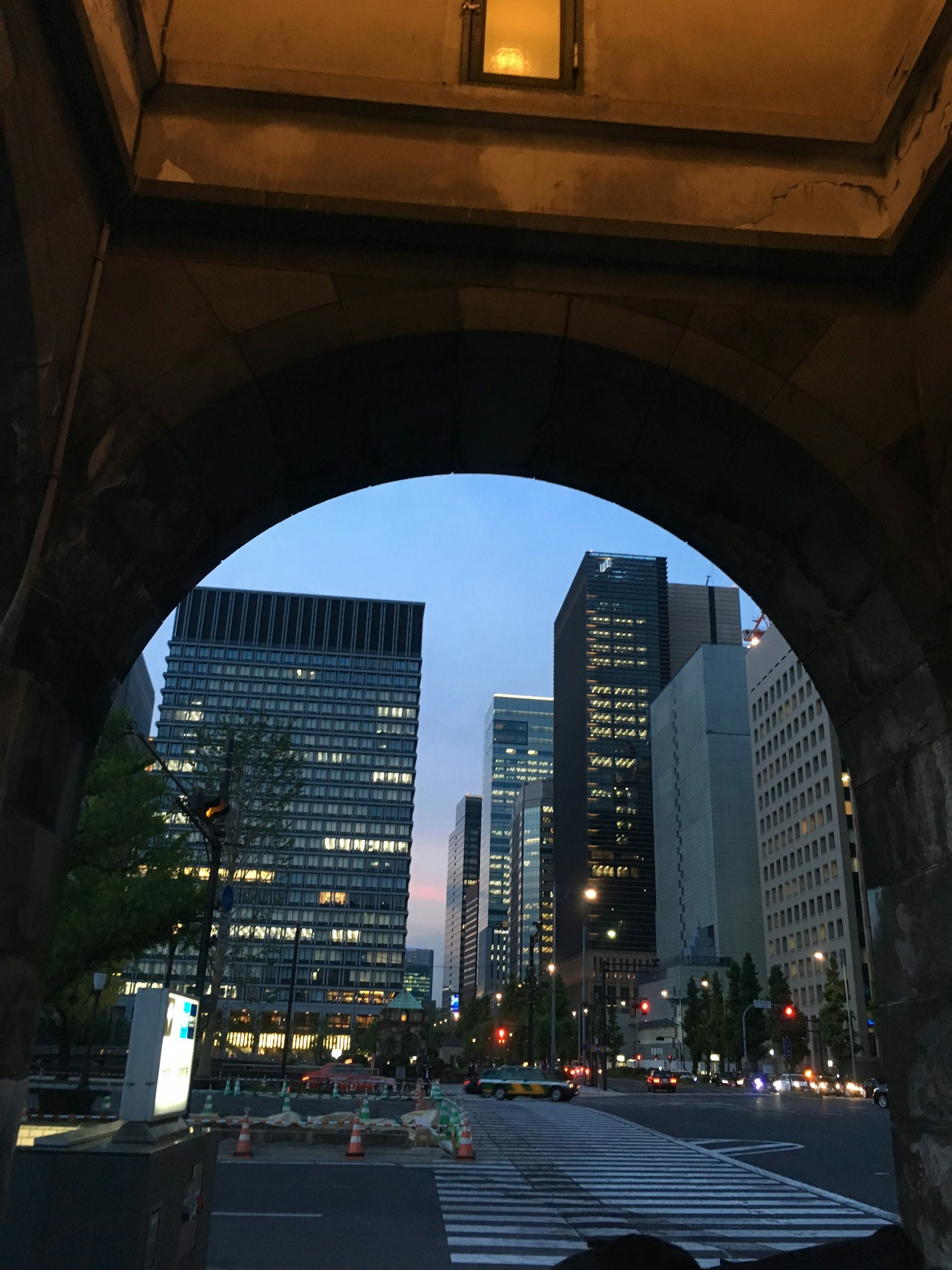 Stadtansicht durch ein Tor mit Wolkenkratzern und Abendhimmel