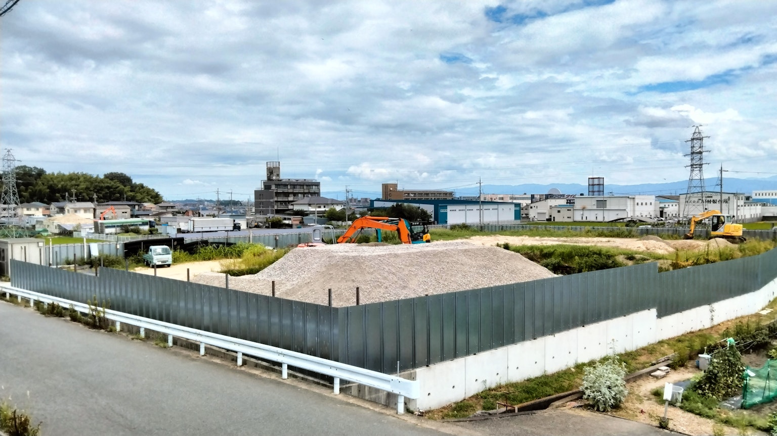 Cantiere con recinzione verde e cielo blu che circonda gli edifici