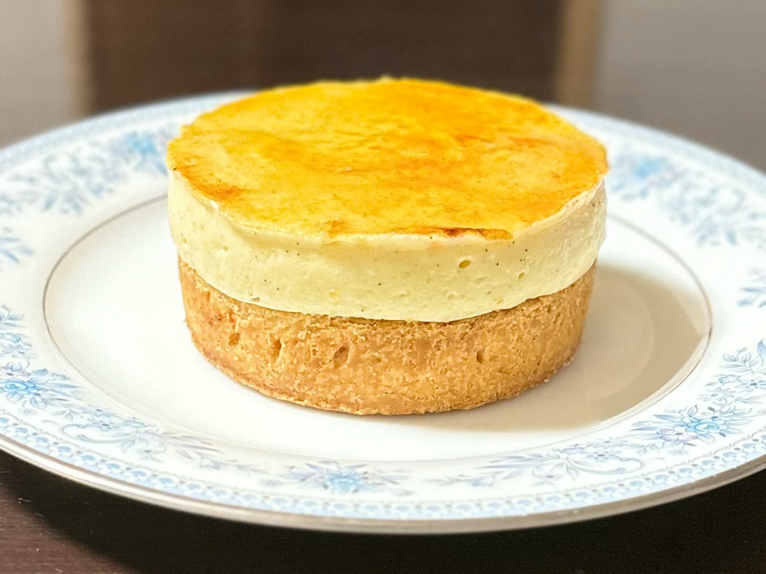Bellissima cheesecake beige su un piatto con motivo floreale blu