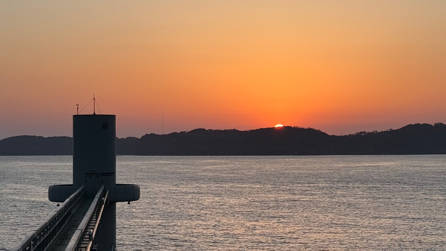 Schöne Landschaft mit einem Sonnenuntergang über dem Meer und der Silhouette einer Brücke