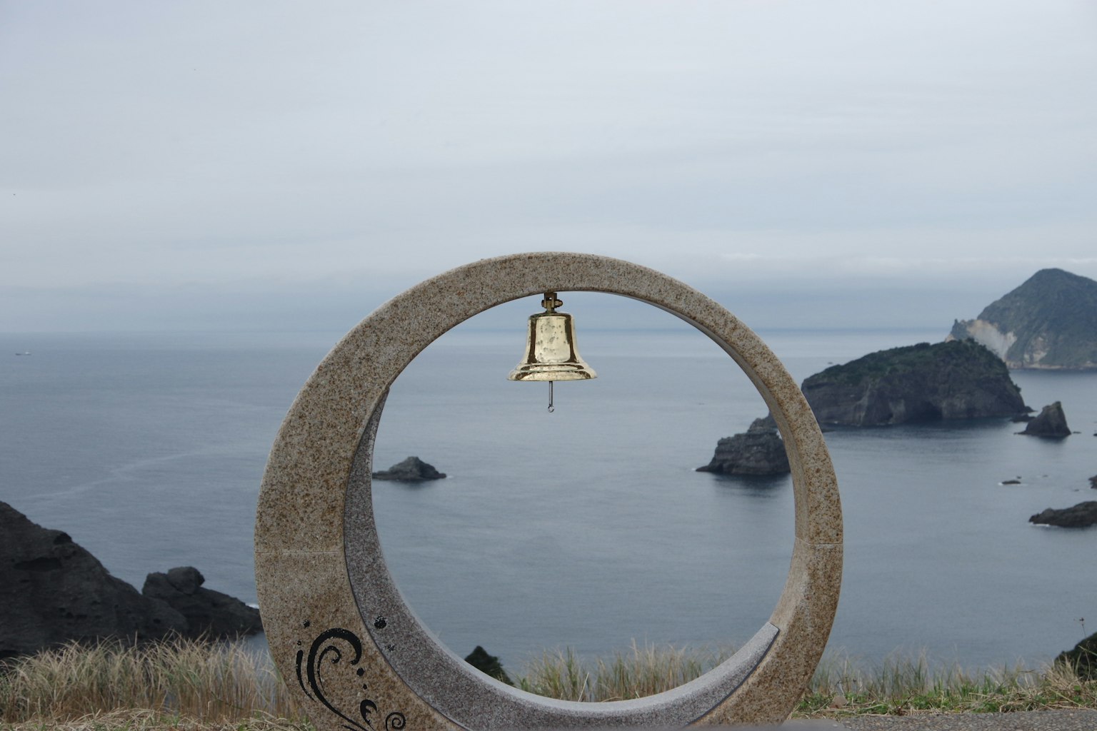 Glocke in einem Steinrahmen mit Blick auf den Ozean