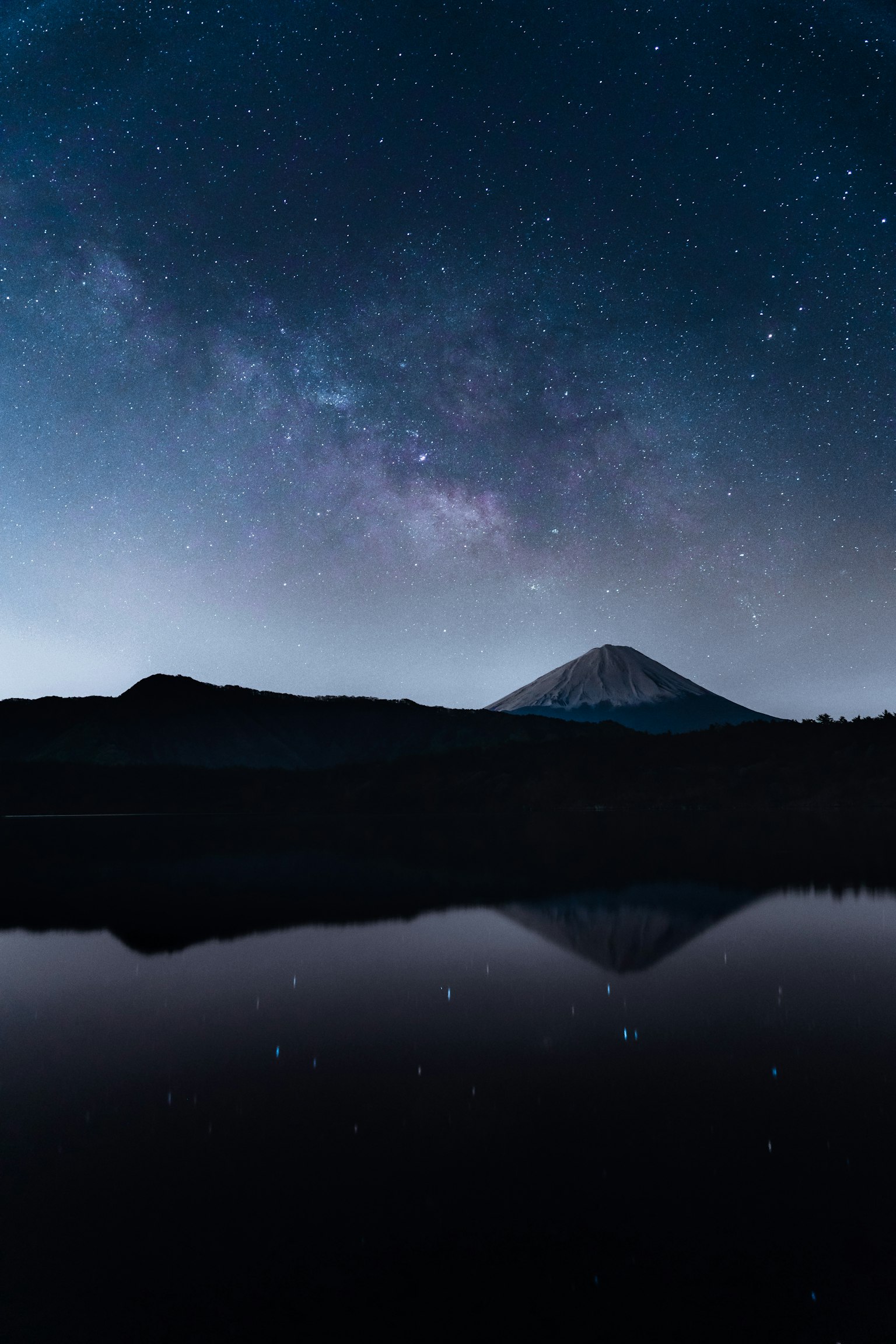 별이 빛나는 하늘과 호수 반사가 있는 멋진 풍경 은하수가 밤하늘을 가로지르며 산의 실루엣이 보인다