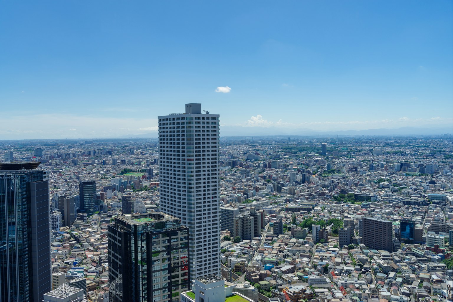 Una vista panorámica de rascacielos y un paisaje urbano extenso bajo un cielo azul claro