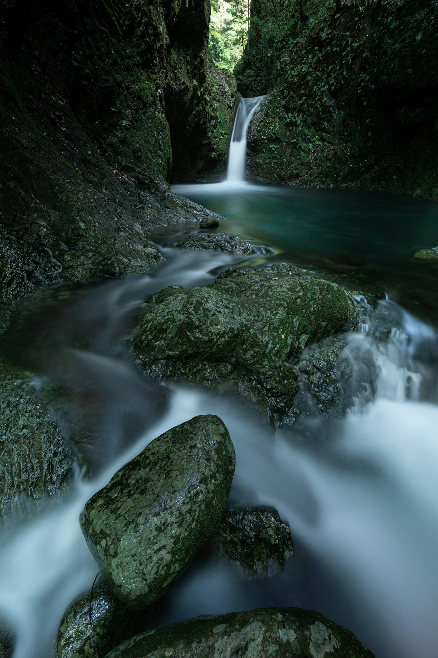 Serene waterfall cascading into a tranquil pool surrounded by lush greenery and rocks