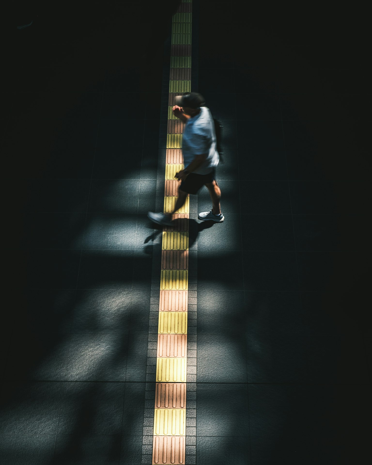 暗い背景の中を歩く人影と光のコントラスト