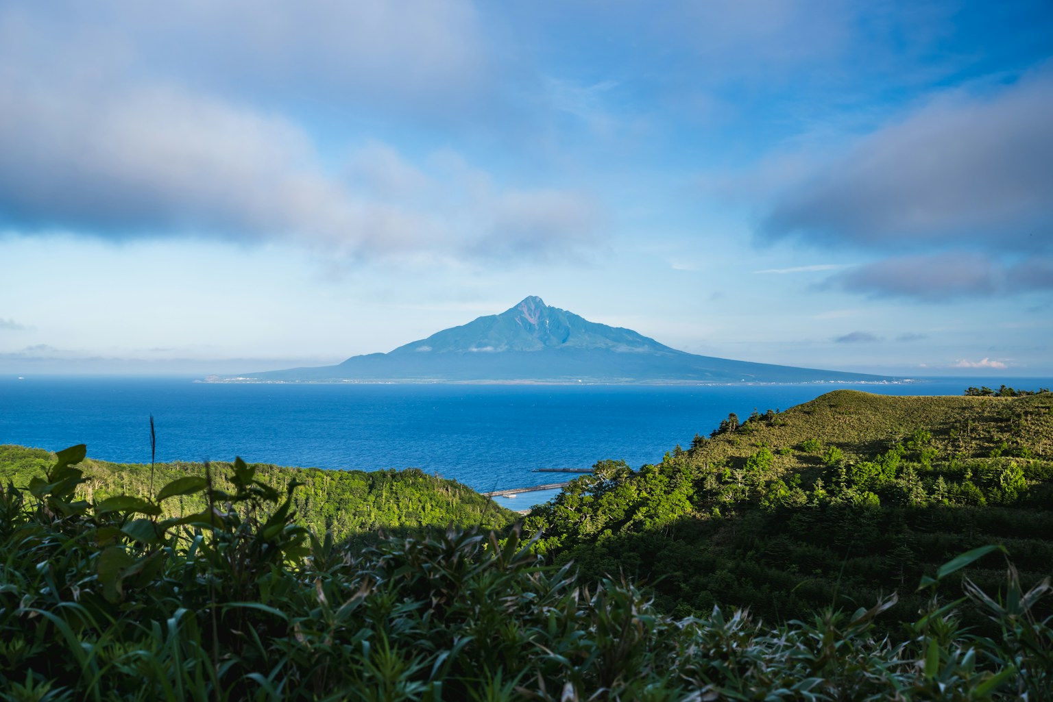 山脉在蓝色海洋和天空下与绿色山丘