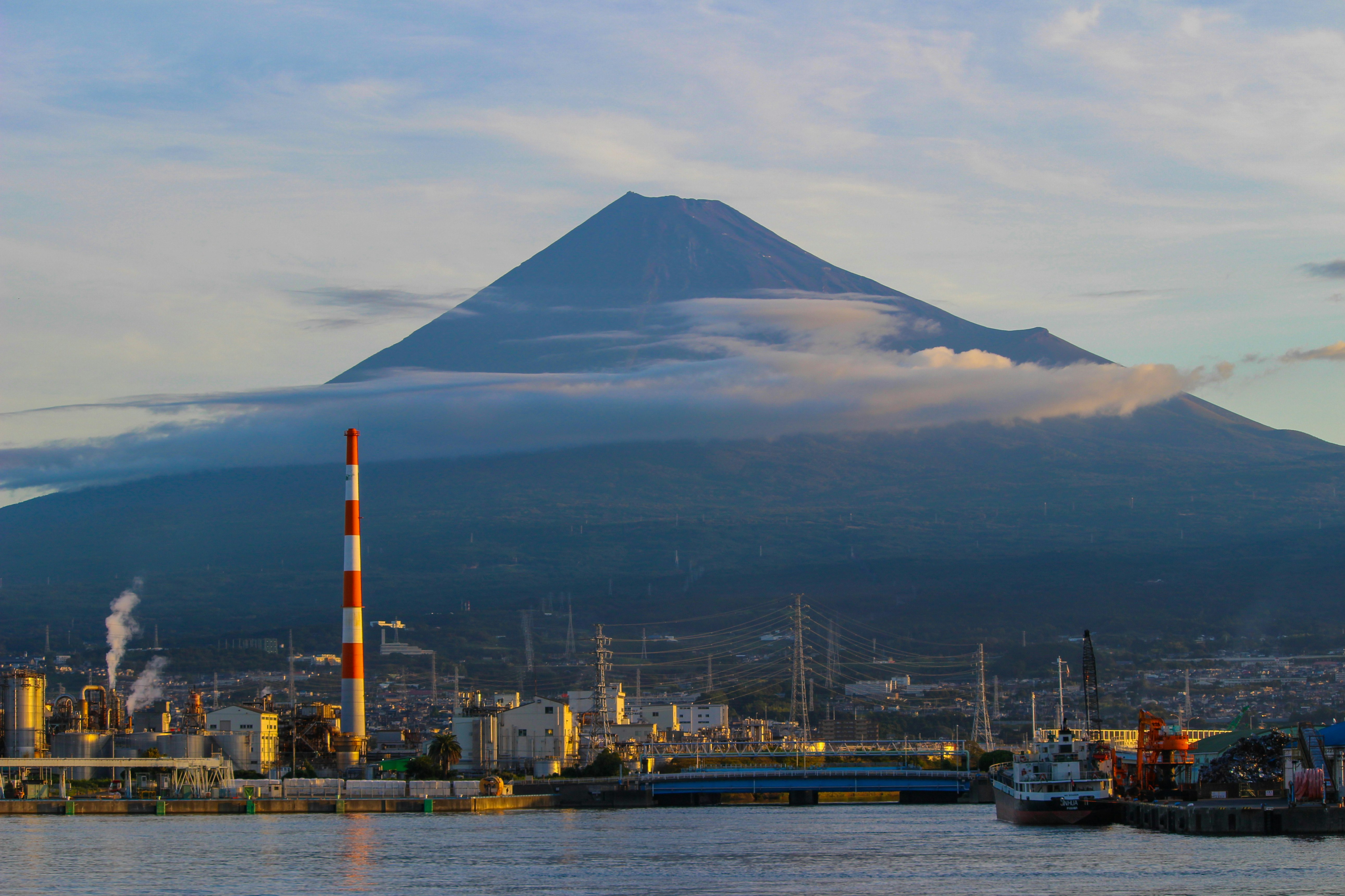 朝の田子の浦から望む富士山と工場のある海辺の風景