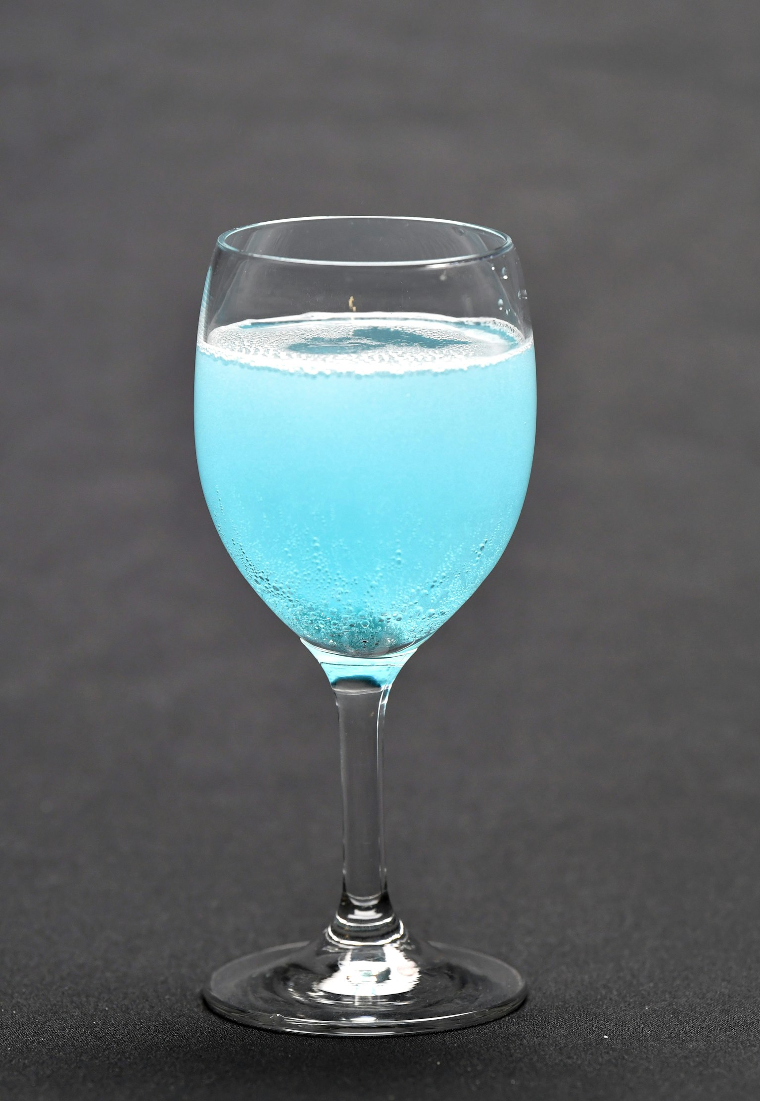 Un bicchiere trasparente pieno di una bevanda blu frizzante