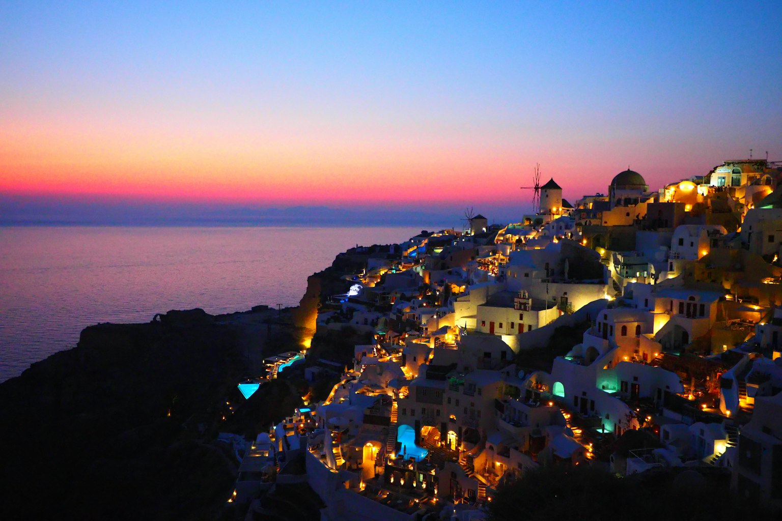 Magnifique vue du coucher de soleil à Santorin avec mer bleue et ciel orange illuminant des bâtiments blancs