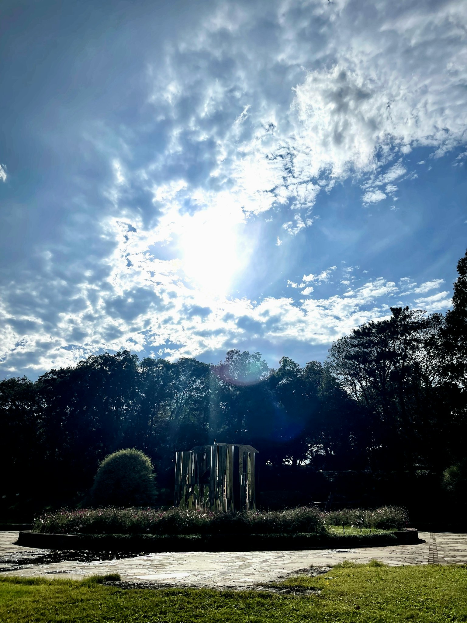 Fountain surrounded by greenery under a blue sky with clouds