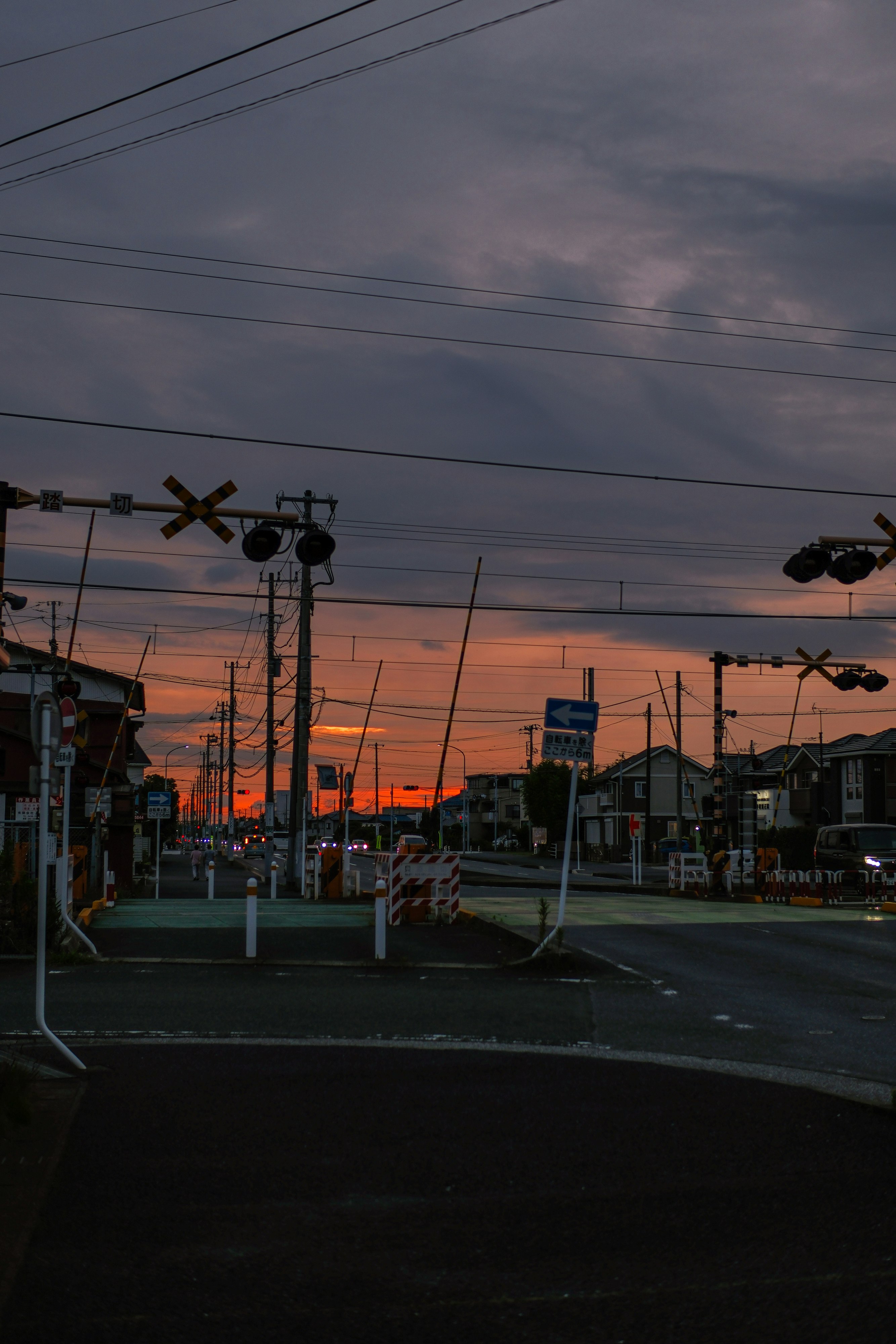 夕焼けの踏切と信号機のある街並み